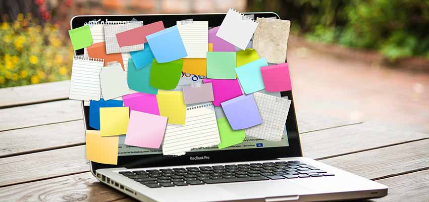 A laptop full of sticky note reminders.
