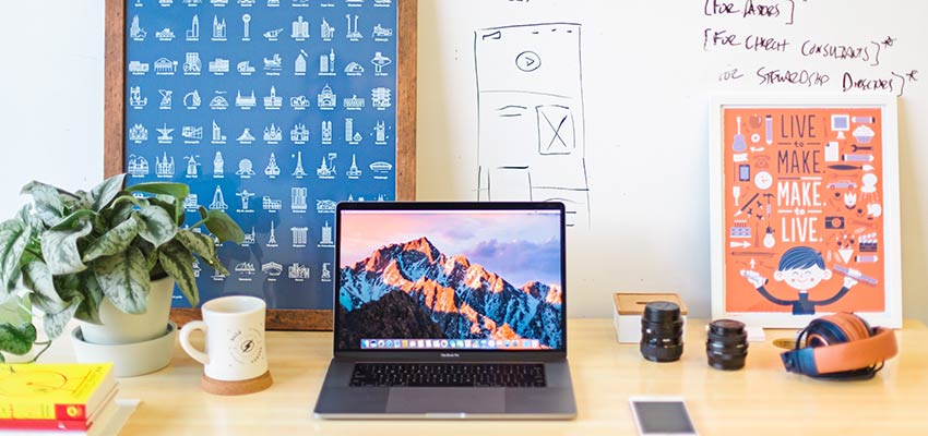 An office desk with laptop and whiteboard.