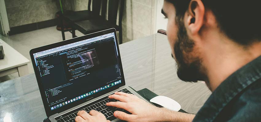 Man writing code on a laptop.