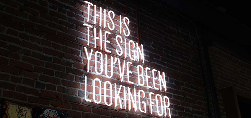 A neon sign that reads "This is the sign you've been waiting for".