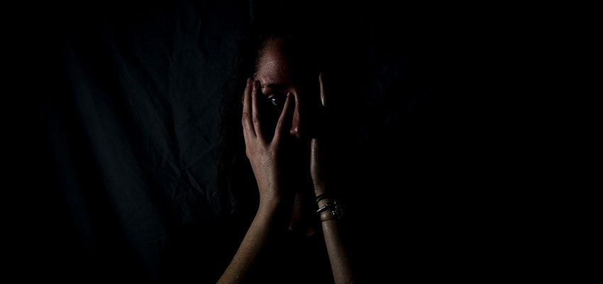 A woman hiding her face with her hands.