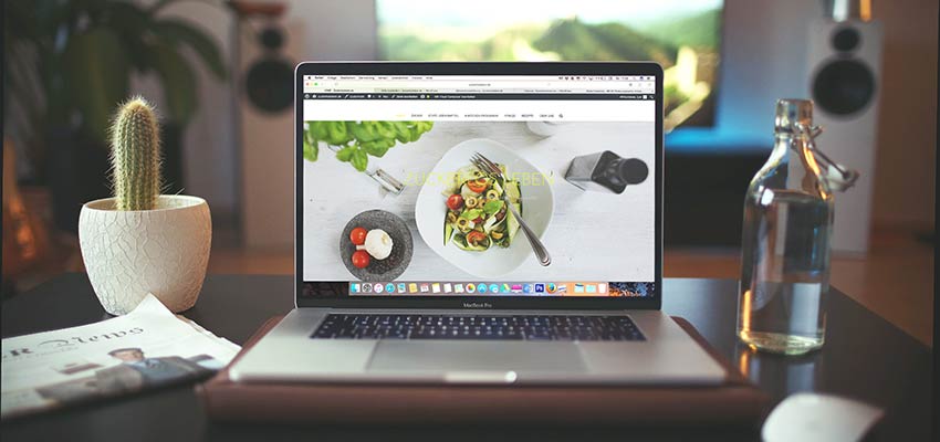 A desk with a laptop and plant.