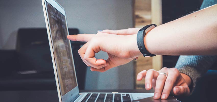 Person pointing at laptop computer screen.