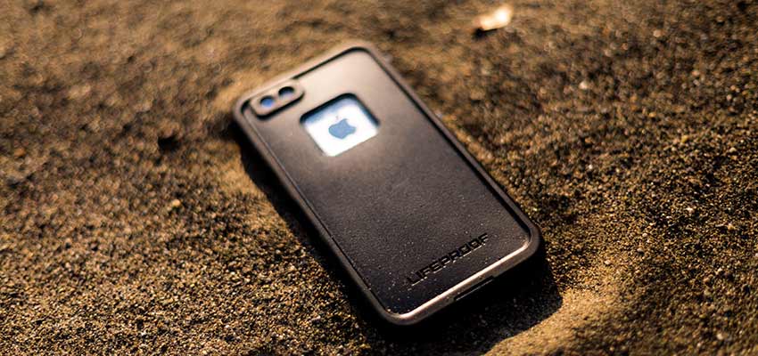 A cellphone sitting on a beach.