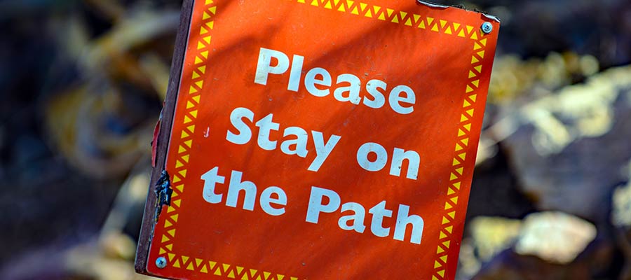A sign that reads "Please stay on the path".