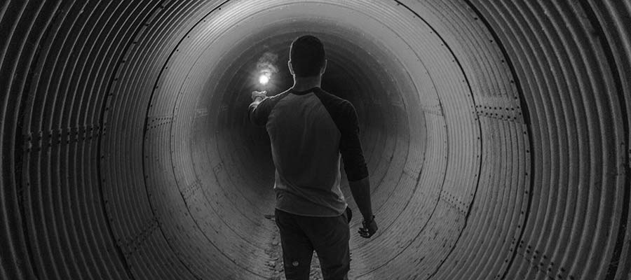 A person holding a light in a dark tunnel.