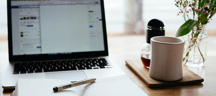 A laptop computer and notepad on a desk.