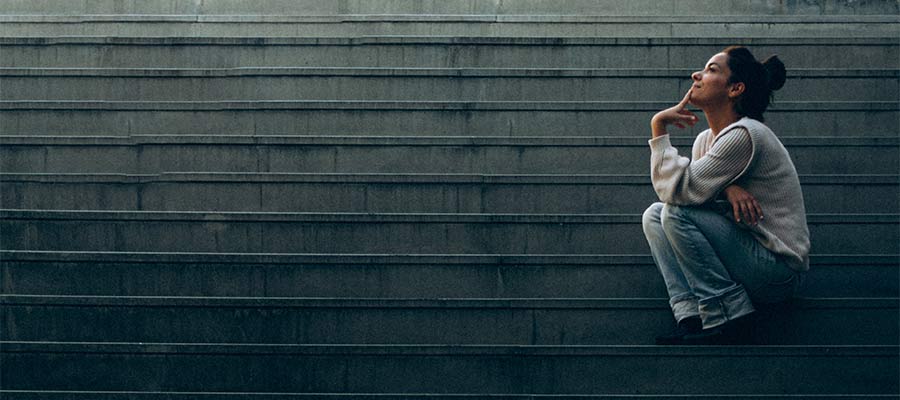 A woman ponders her thoughts while sitting on stairs.